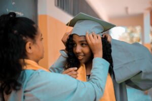 Two young women get ready for graduation ceremony.
