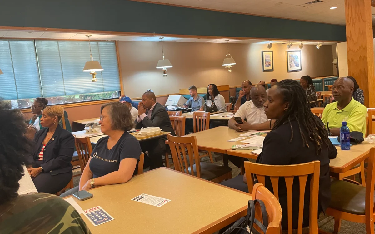 South Fulton Democrats seated at tables during a monthly meeting, with voter registration handouts in front of them.