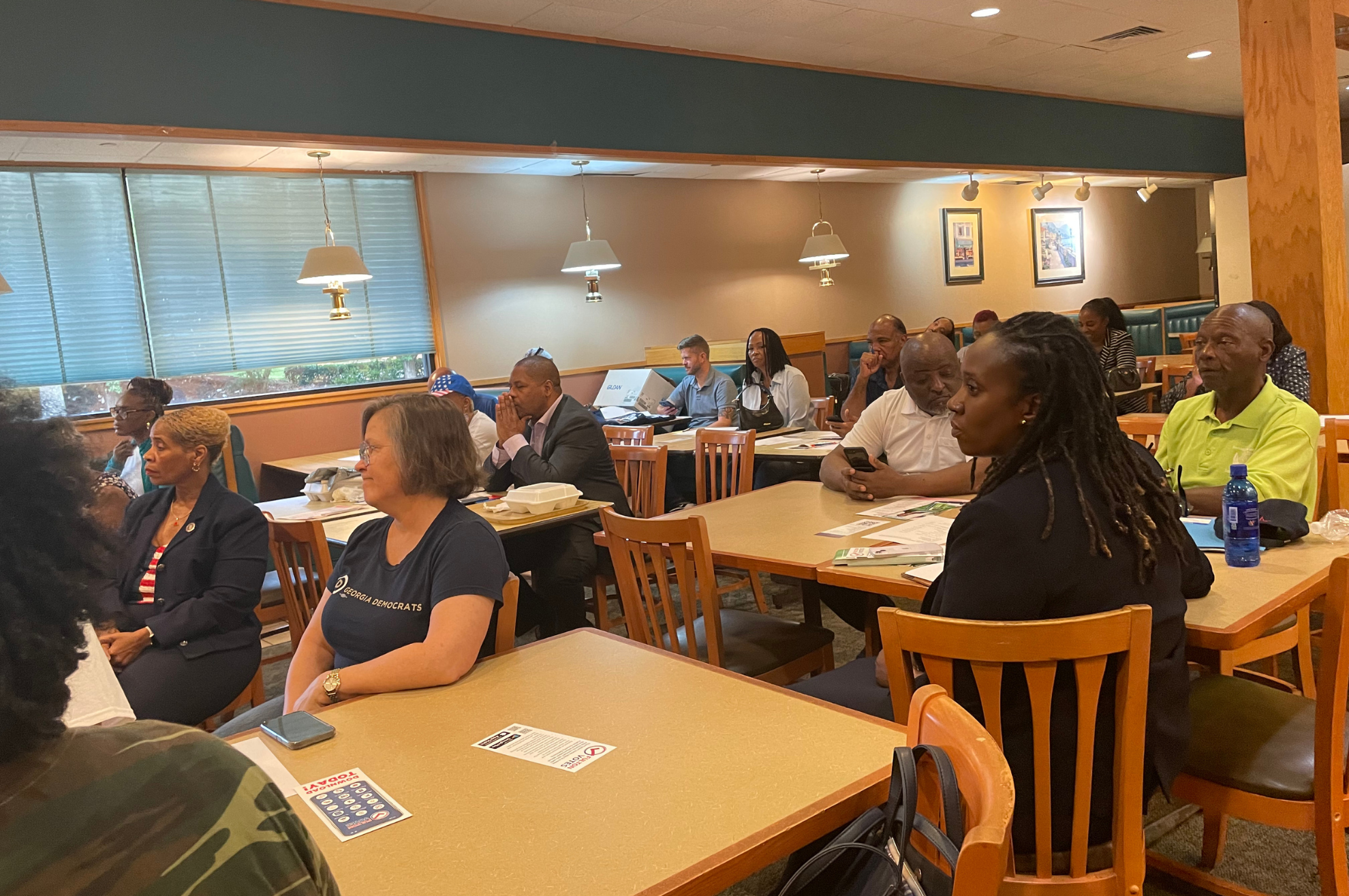South Fulton Democrats seated at tables during a monthly meeting, with voter registration handouts in front of them.