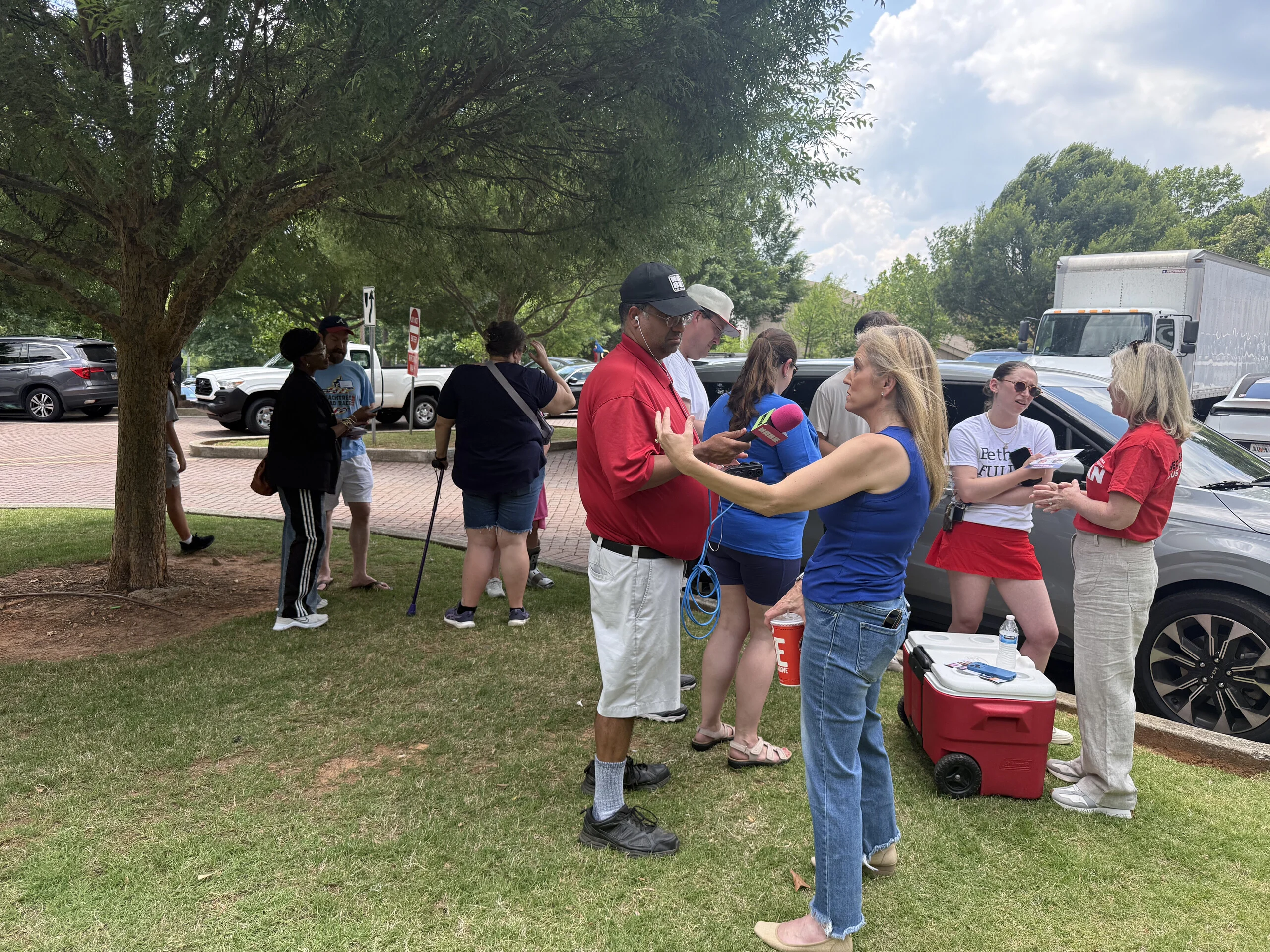 Fulton County Democrats volunteers gathered outdoors beside parked cars, organising before heading out to canvass.