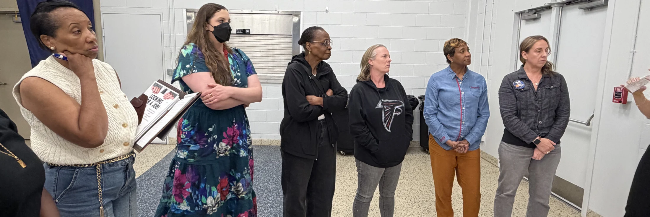 A group of Fulton County Democrats standing together in conversation, one holding printed papers.